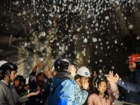 Children wearing helmets enjoying an interactive guided tour with lights and sounds inside the Landesplattenberg Engi.