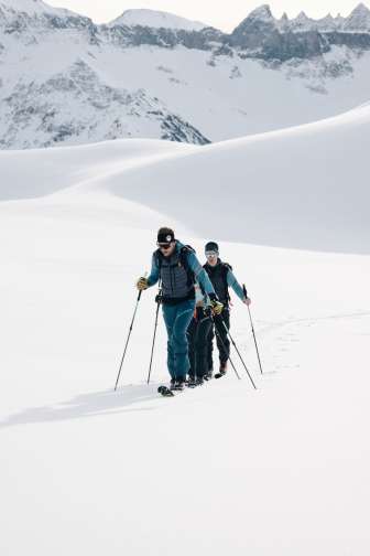 Drei Skitourengeher steigen mit Fellen durch Schnee