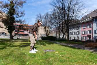 A worker of the tourist information in Glarus giving a golfer his equipment for Urban Golf