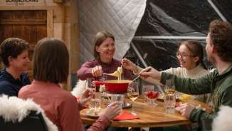A group of people enjoying fondue in the fondue iglu at Grotzenbüel