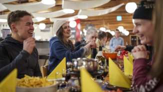 A gruop of young people is enjoying cheese fondue at the mountain restaurant Ämpächli.