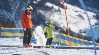 Child learning to ski in the beginner area in Elm with a ski instructor