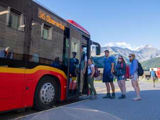 Wandergruppe steigt in Bus vor Bergkulisse im Glarnerland ein