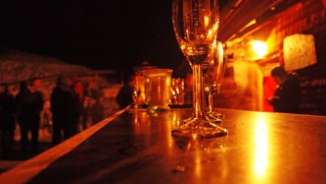 Dim lit bar with glasses, orange light, people in the background.