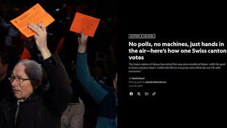 National Geographic article showing an outdoor voting scene at the Glarus Landsgemeinde, where participants hold up orange voting cards. The image focuses on raised hands and voting cards in a crowd, illustrating Switzerland’s traditions
