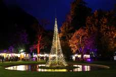 A large Christmas tree with lights and market stalls at night