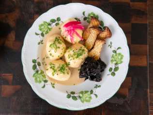 A plate featuring Ziger dumplings in onion sauce, served with king oyster mushrooms, dried plum compote, and pickled onions.