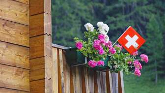 Decor on a balcony for the national celebration of Switzerland with flowers and the swiss flag.
