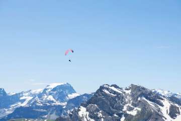 A paraglider soaring above Braunwald with the Glarus Alps in the background.