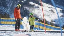 Child learning to ski in the beginner area in Elm with a ski instructor