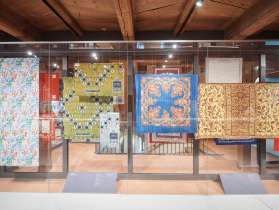 Historical and modern fabric patterns displayed in a glass case at the textile exhibition in Freulerpalast Näfels.