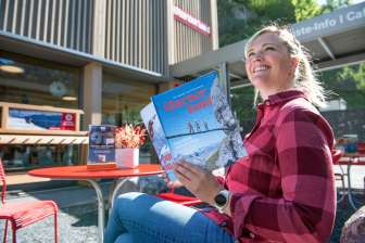 Frau liest das Glarnerland Magazin vor der Gästeinformation und plant ihren Aufenthalt im Glarnerland
