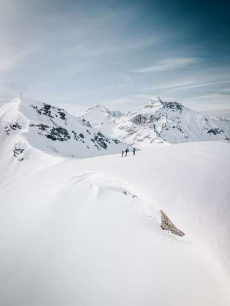 Skitourengruppe auf verschneitem Grat mit Alpenpanorama