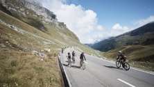 Gruppe von Rennradfahrern fährt während des Klausen Monument über den Klausenpass.