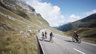 Road cyclists climbing the Klausen Pass during the Klausen Monument against a spectacular Alpine backdrop.