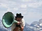 Schauspieler Gian Rupf mit historischem Grammophon vor einer alpinen Bergkulisse